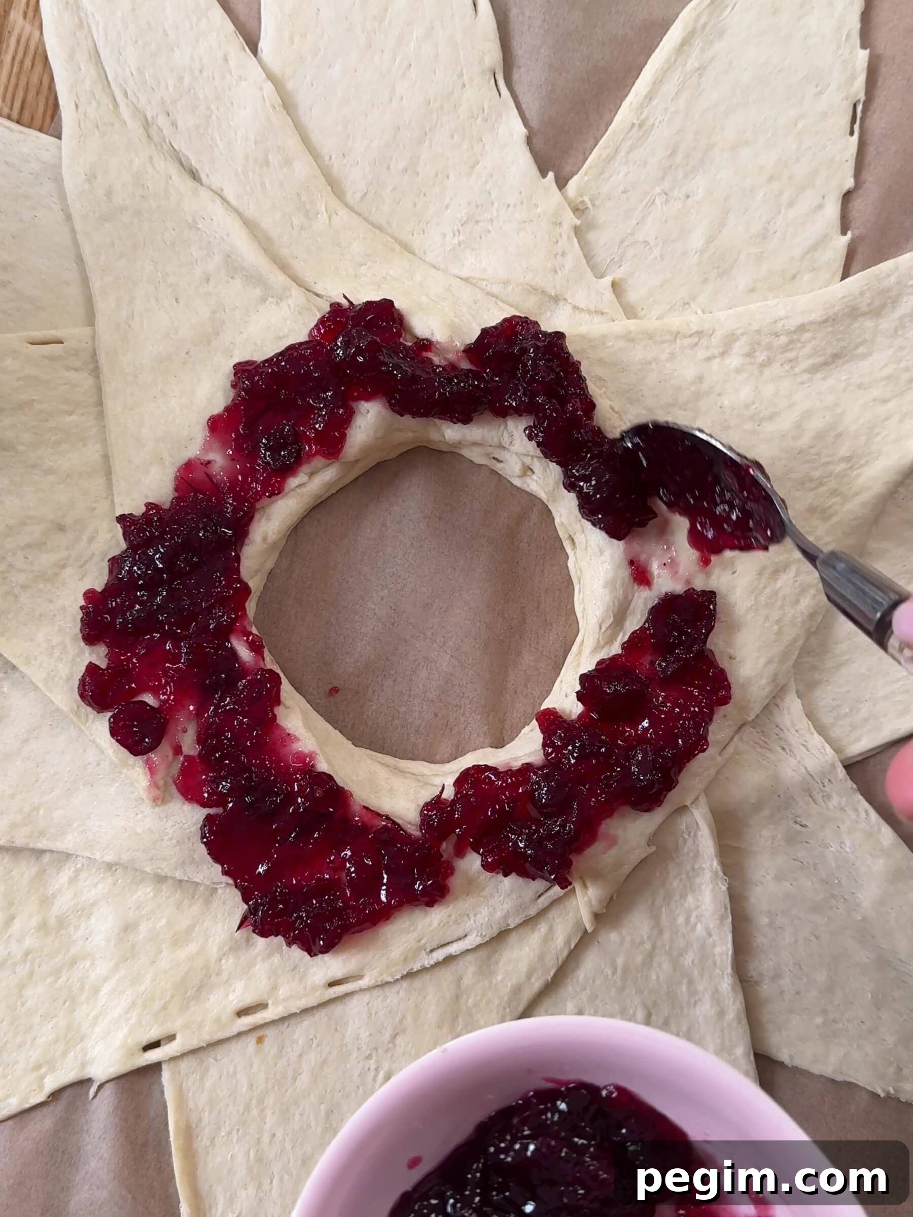 Adding cranberry sauce around the croissant dough