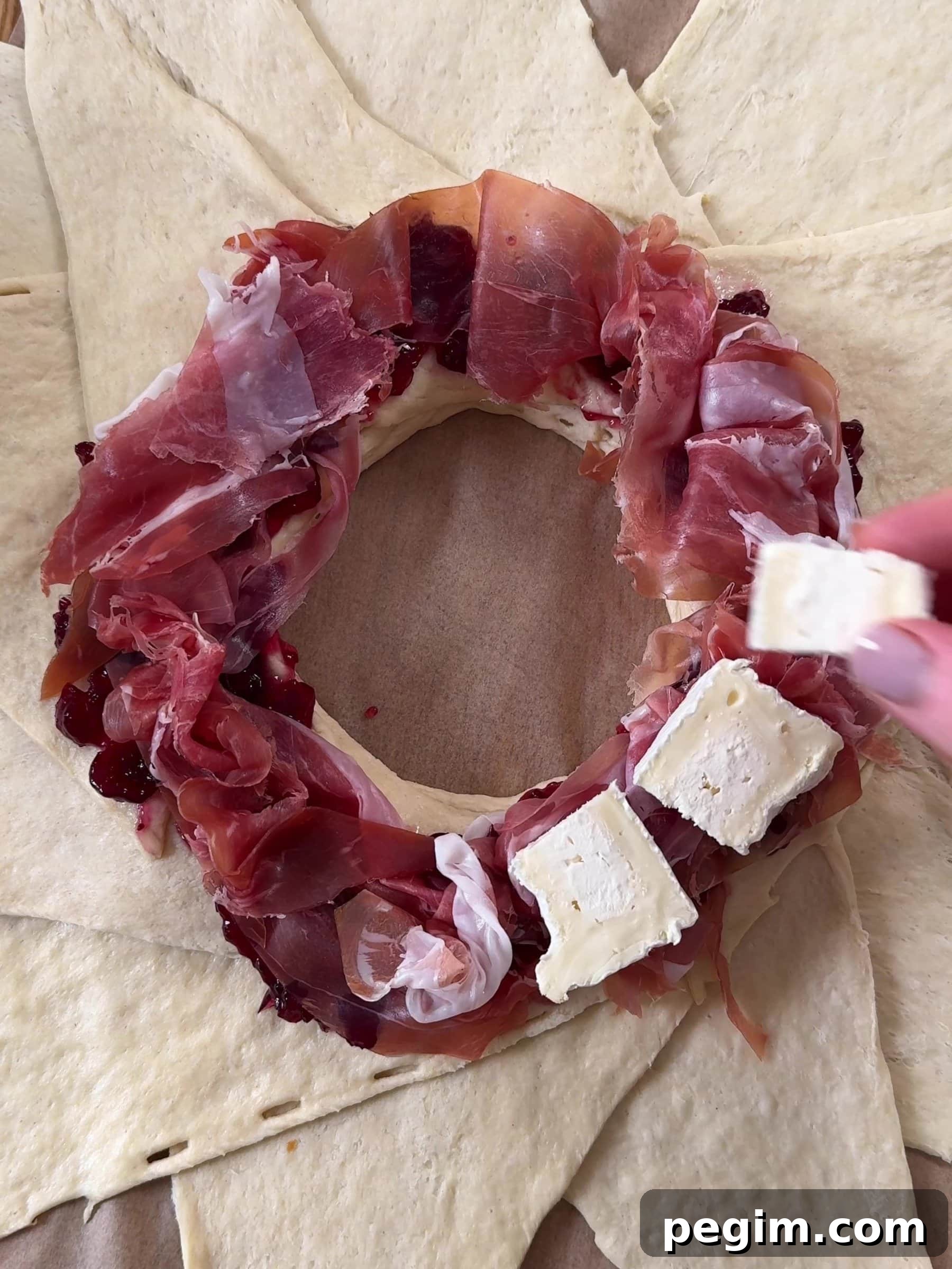Adding parma ham and brie on top of the dough