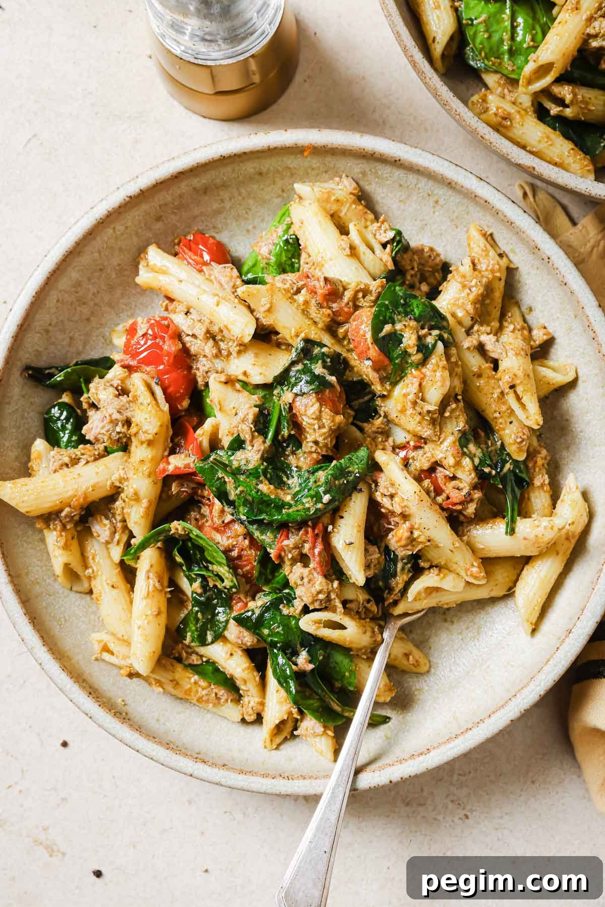 A bowl of tuna pesto pasta with a fork.