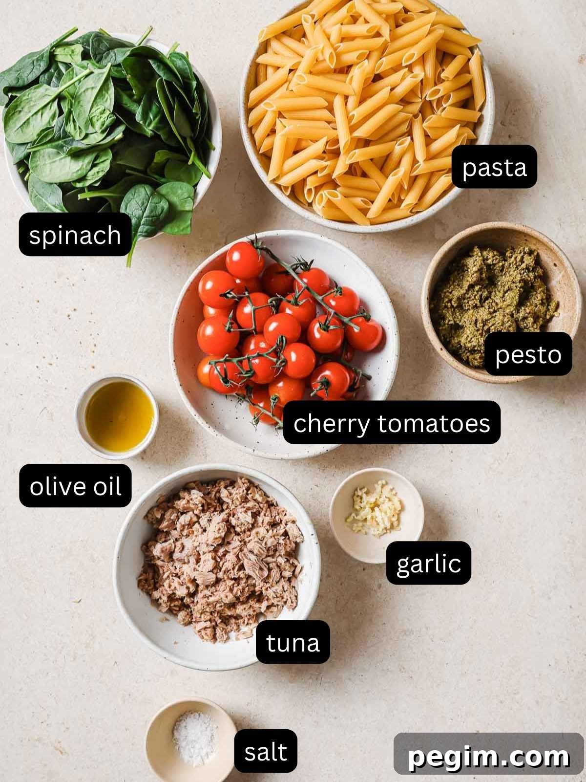 Ingredients for a pasta dish with tomatoes, spinach and tuna.