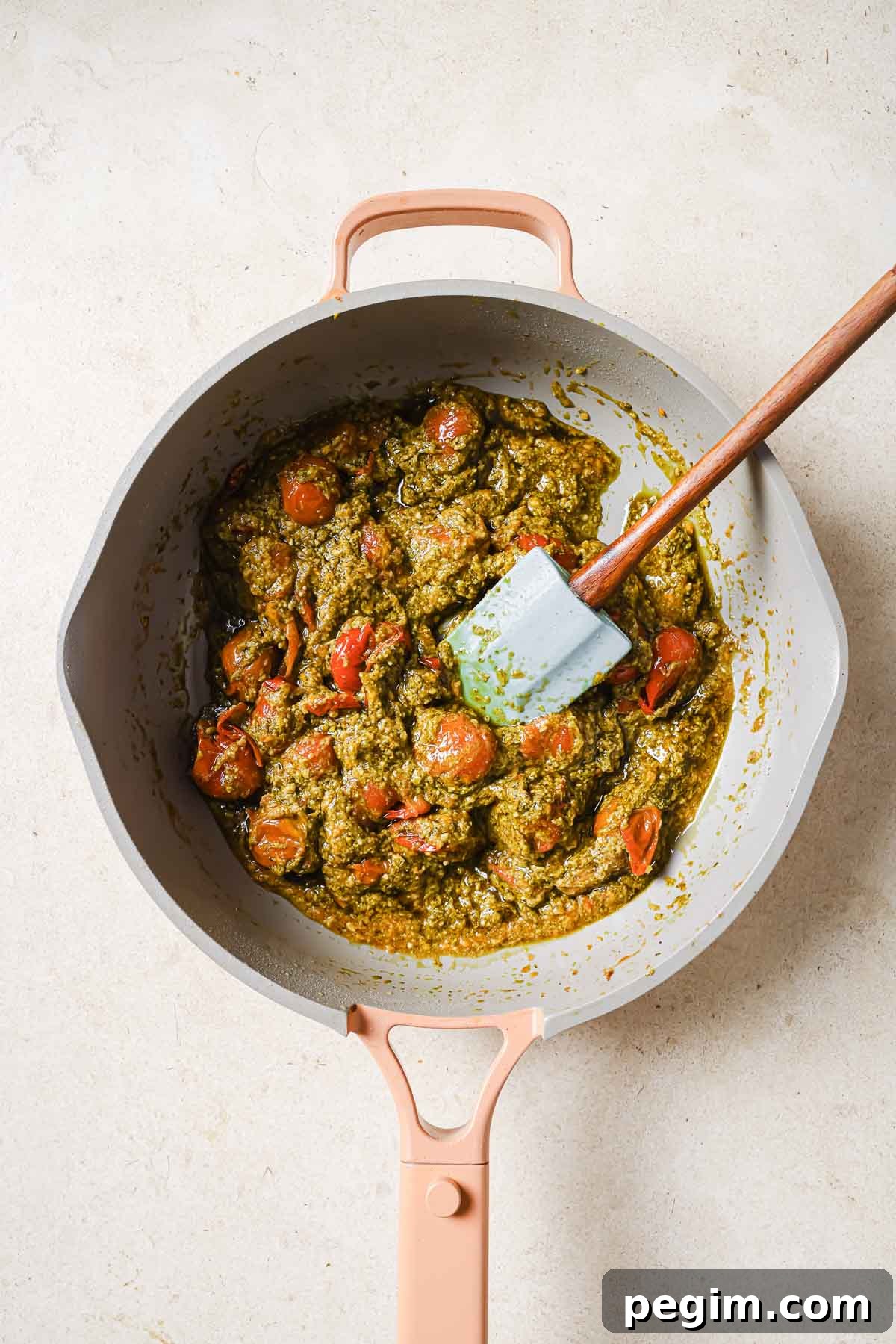 A frying pan with cherry tomatoes and pesto.