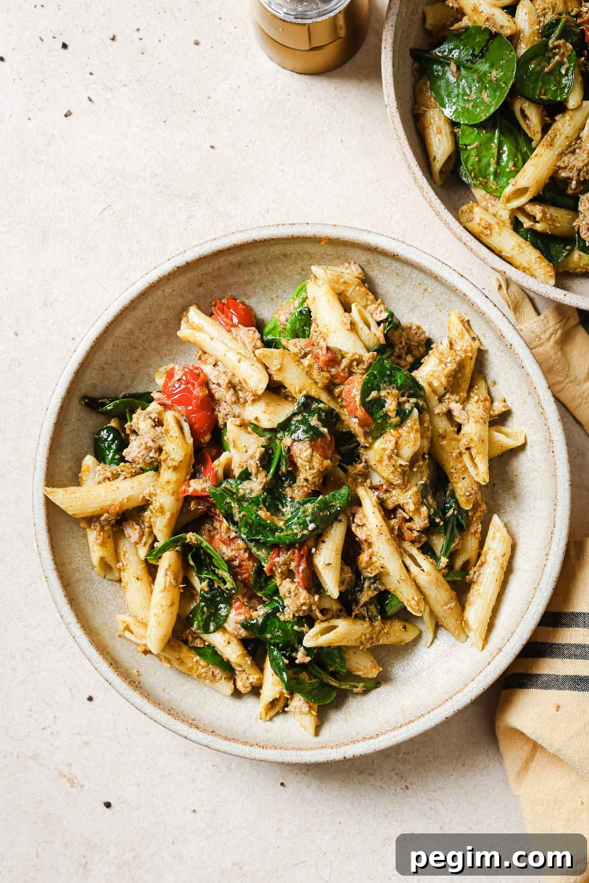 Two bowls of pasta with spinach and tuna.