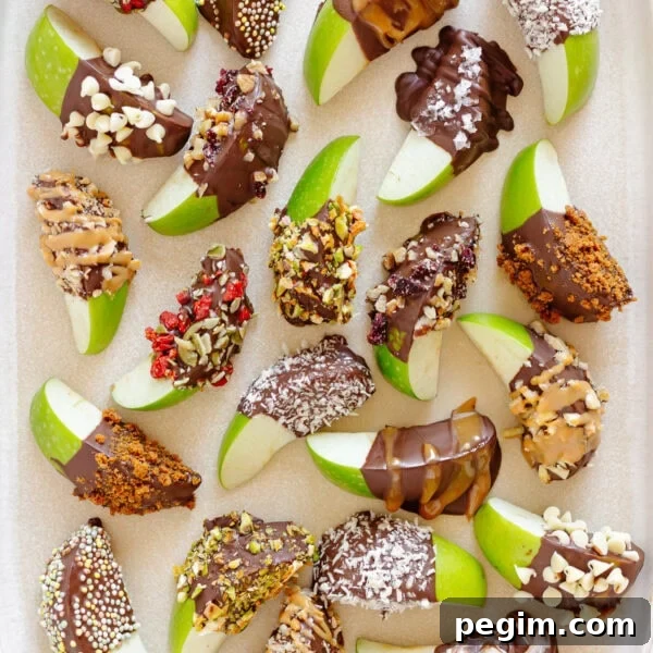A variety of chocolate dipped apple slices on a cream colored serving platter.