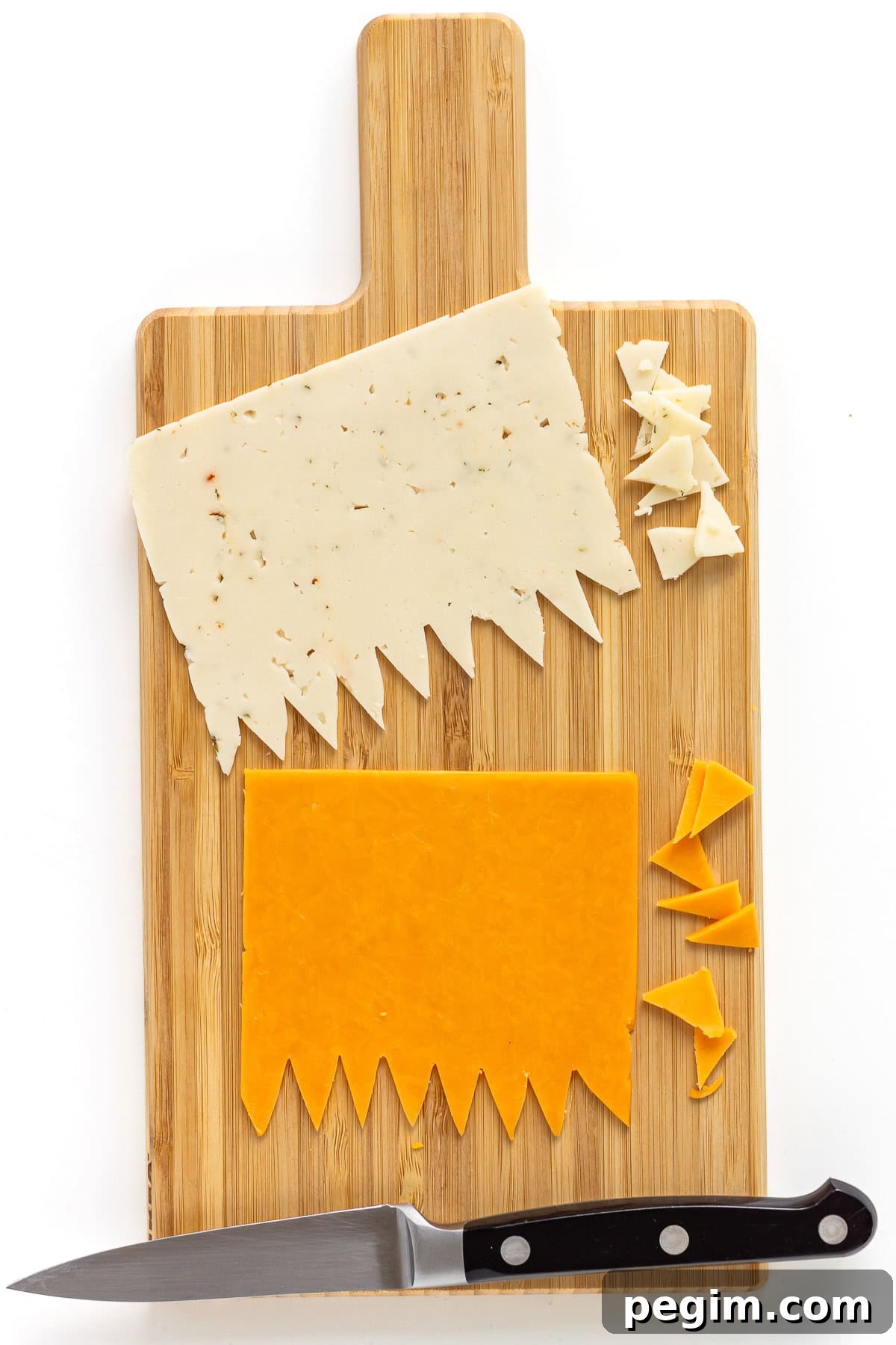 Two cheese slices on cutting board with zigzag pattern cut out along one edge.
