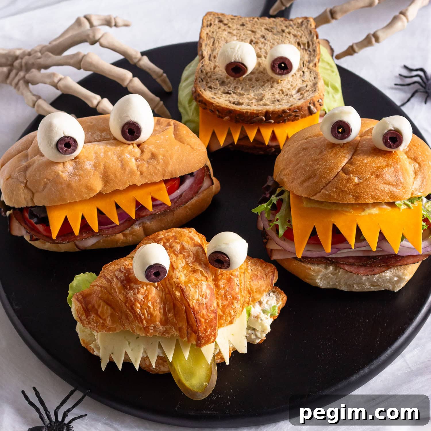 Halloween monster sandwiches on a black round serving board.