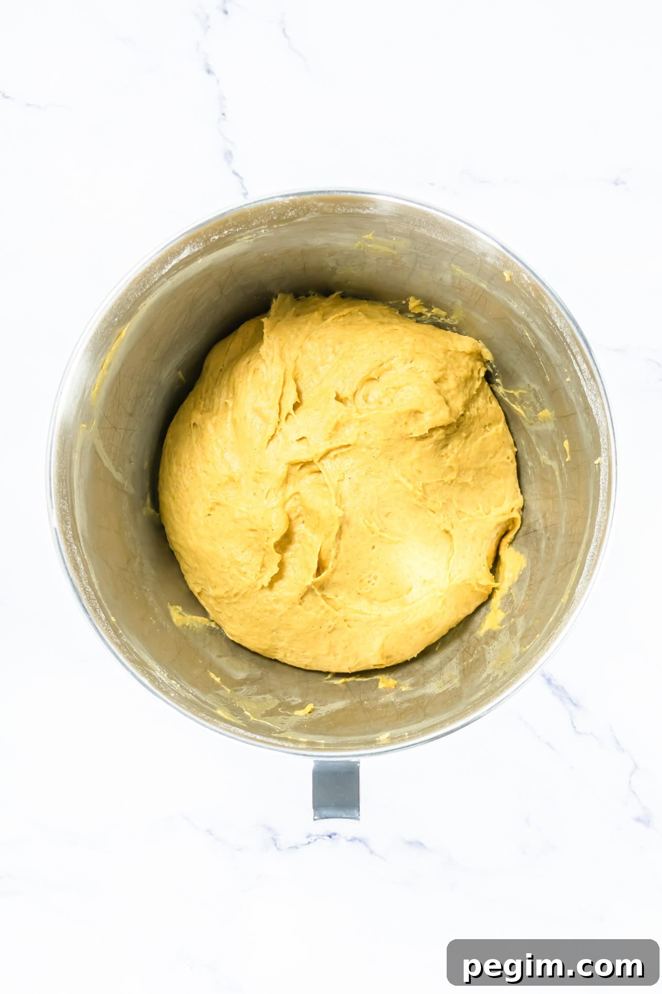 Creamy yellow dough in a metal mixing bowl, ready for baking or cooking. 