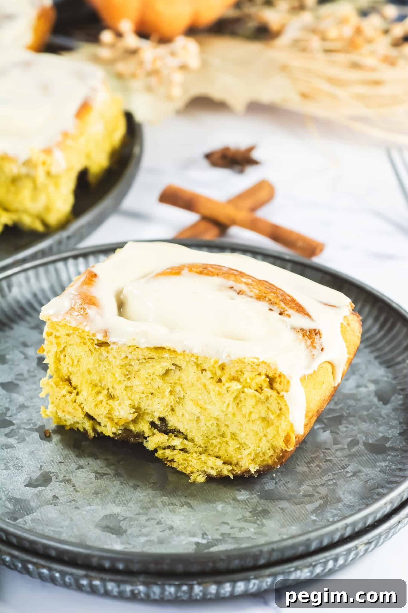 Moist cinnamon roll with icing on a silver plate, close-up shot.