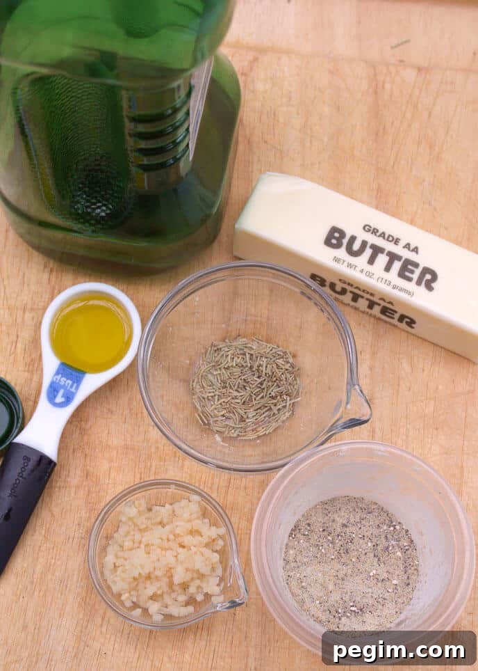 A bottle of oil, a stick of butter, a tablespoon of oil, dried rosemary, minced garlic, and ground pepper sit on a wooden surface next to a pile of Crock Pot Red Potatoes.