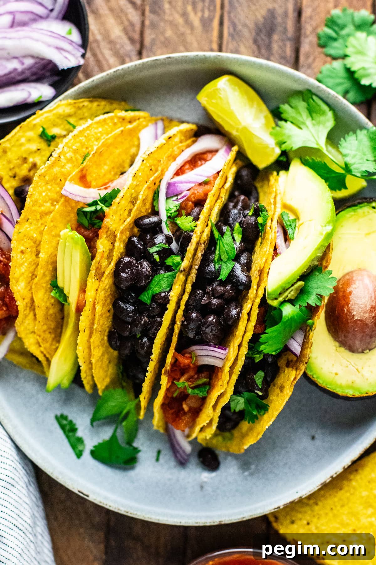 a group of black bean tacos on plate with condiments.