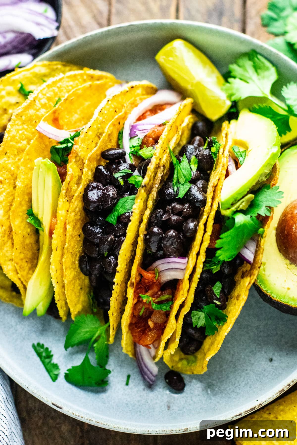 a group of black bean tacos on plate with condiments.