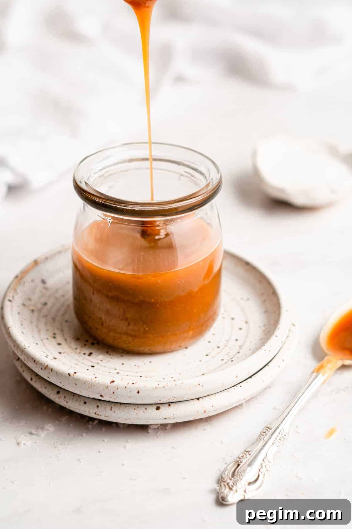 Caramel sauce drizzling into a jar.