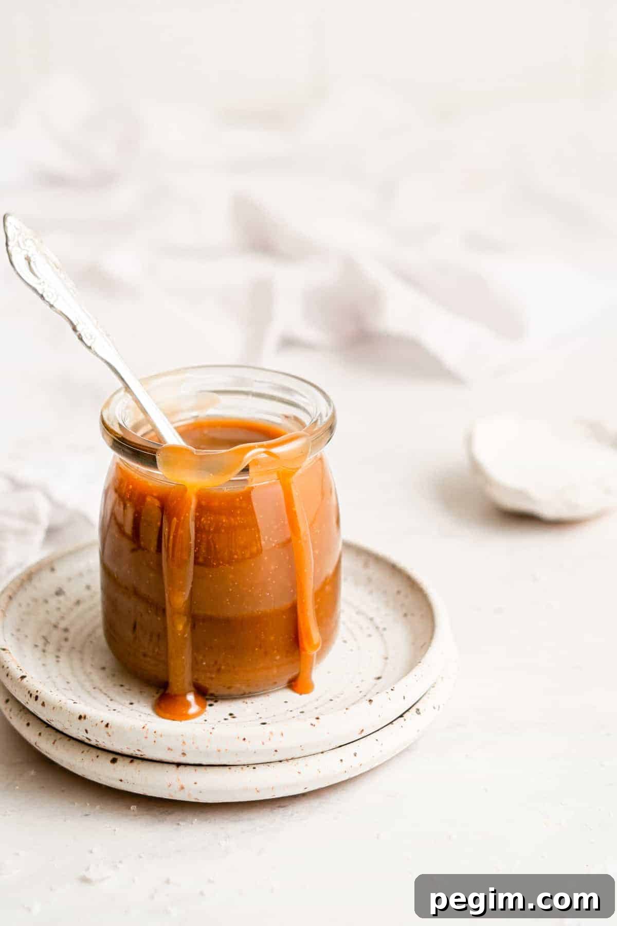 Vegan caramel sauce in a jar, with some caramel dripping down the side.