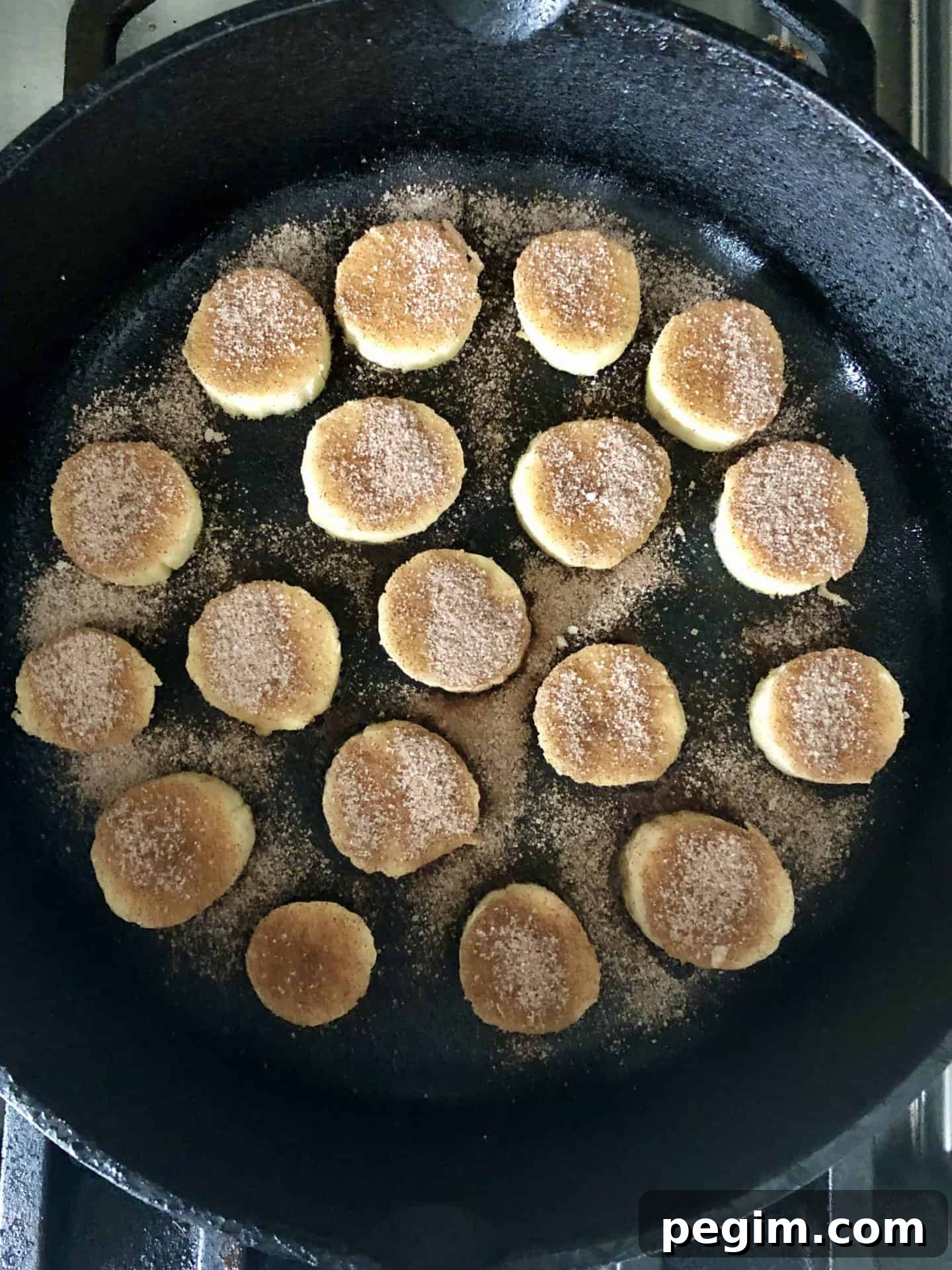 Bananas with cinnamon sugar on top in cast iron pan overhead shot