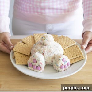 Easter dessert shaped into a bunny butt displayed on white plate surrounded by graham crackers on wood cutting board.