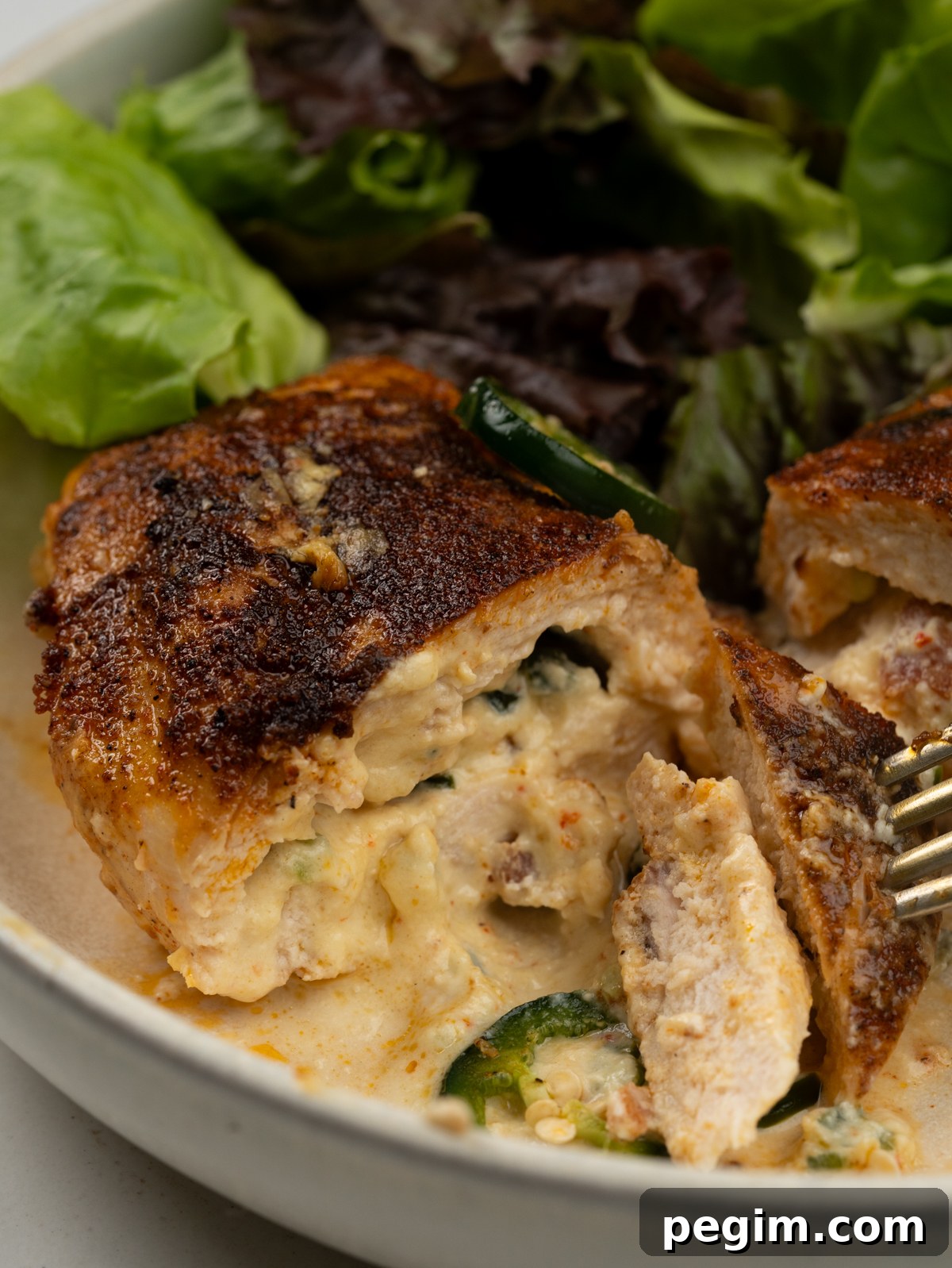 Half cut jalapeno popper stuffed chicken breast served with green salad
