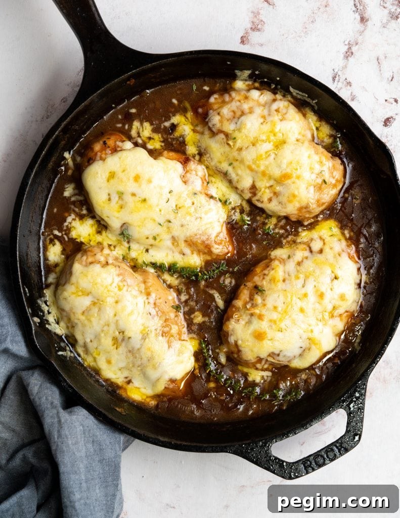 Chicken breast topped with cheese in a skillet of french onion gravy