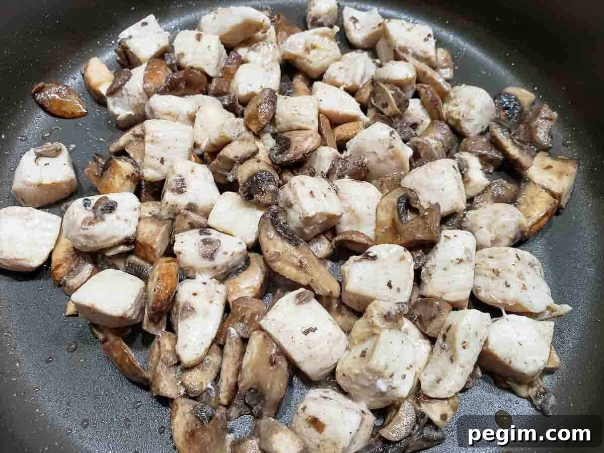 diced chicken and mushrooms cooking in a pan