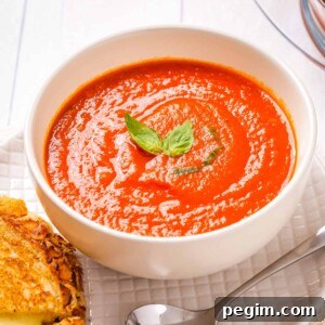 A close-up view of instant pot tomato soup placed in a white bowl with cheese toasties on the side.