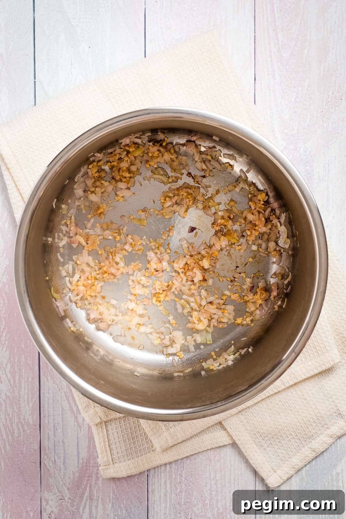 Overhead view of browned, sauteed shallots and garlic in a pot.