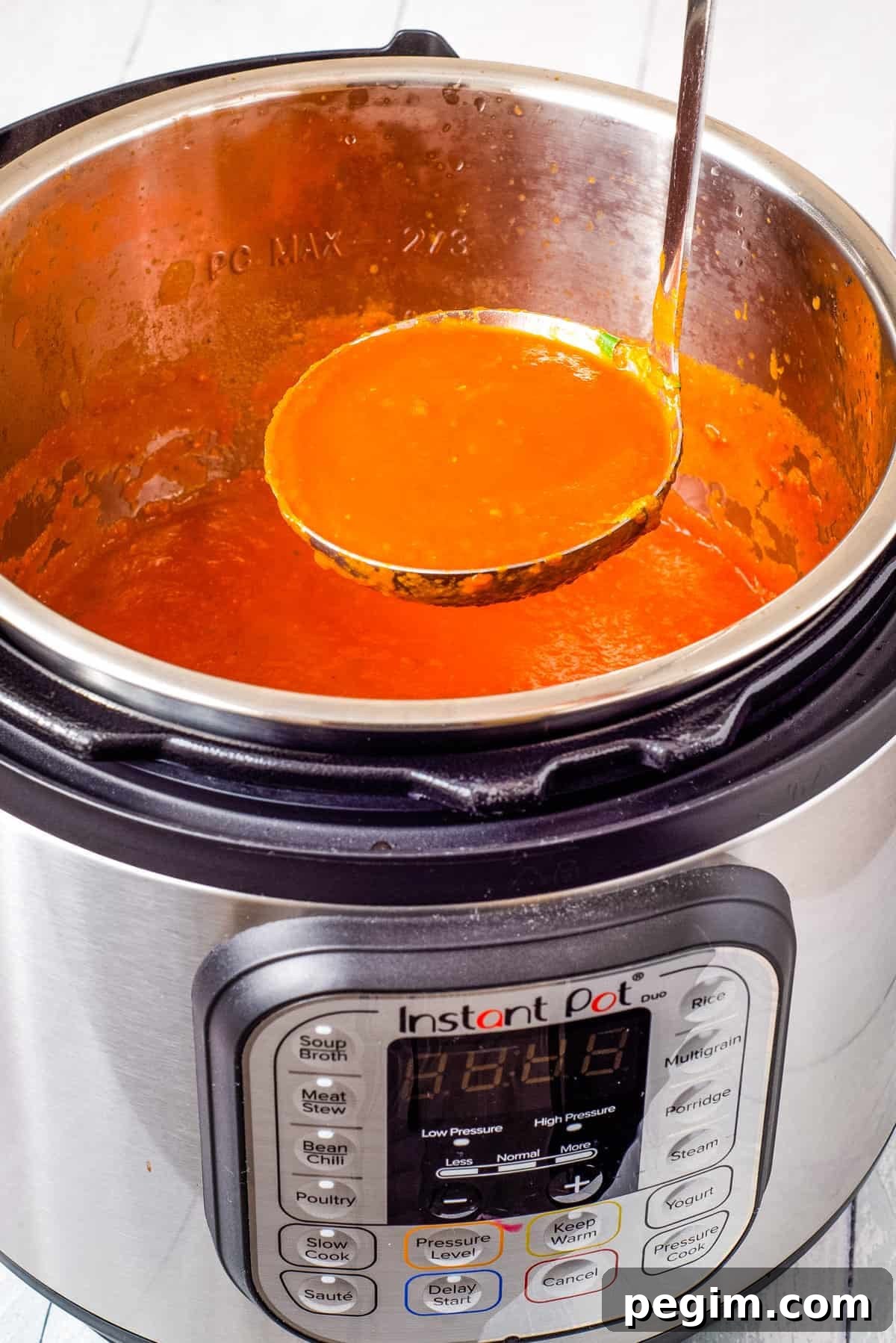 A close-up view of tomato soup being scooped out of the instant pot.