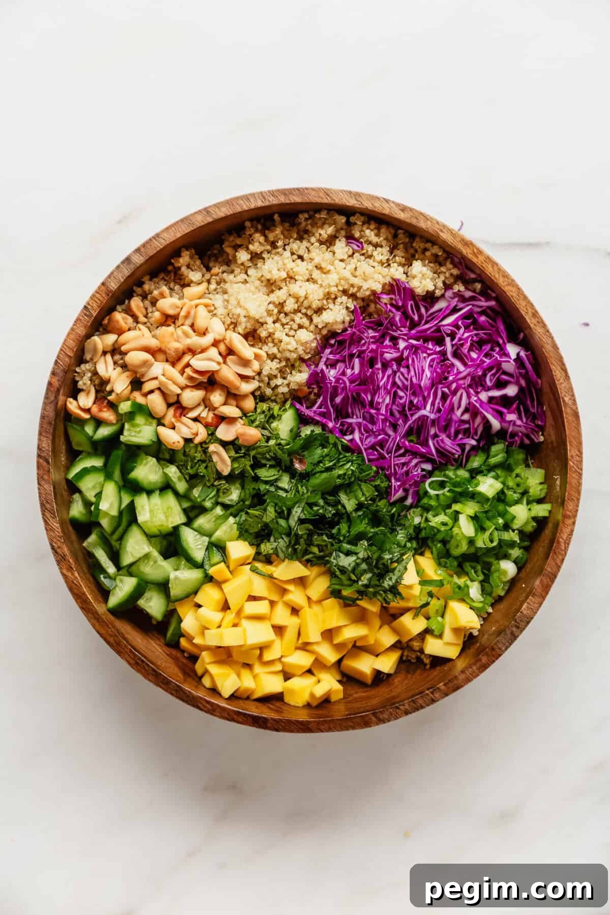 Ingredients for a Thai quinoa salad in a wood salad bowl.
