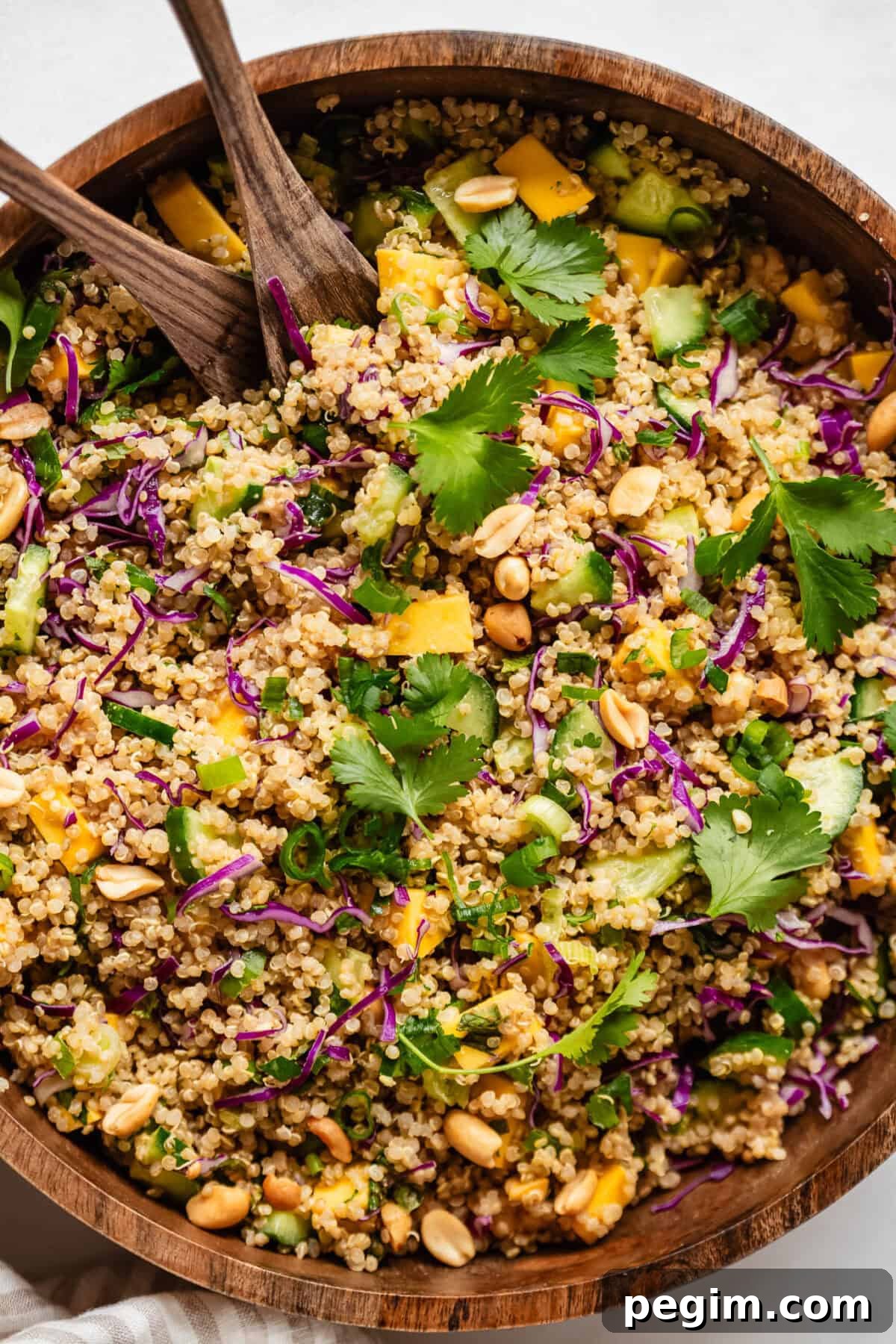Quinoa salad with mango, cucumber, scallions and cilantro in a wood salad bowl.