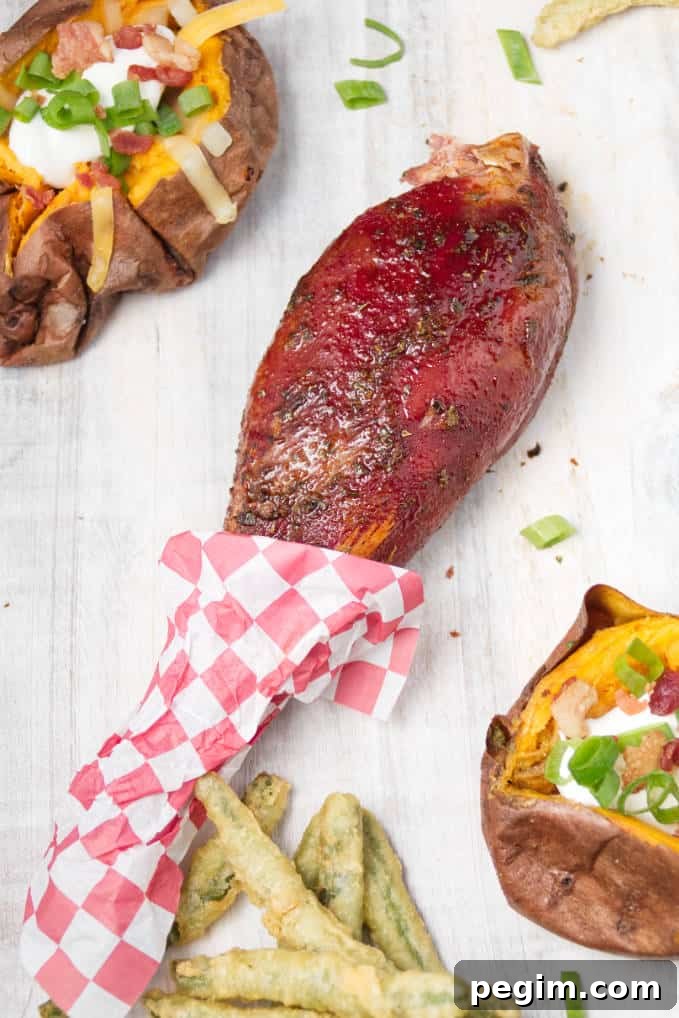 Smoked wild turkey leg laying on white cutting board with loaded baked sweet potatoes and some fried green beans