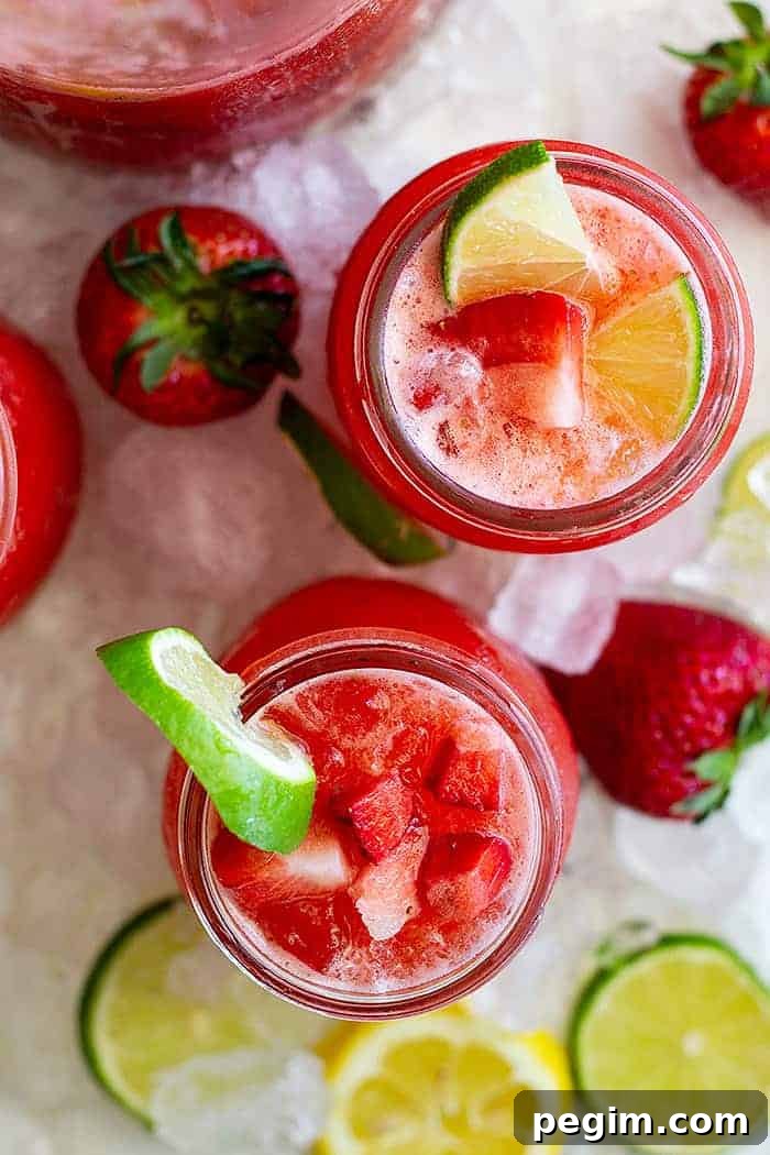 overhead: several glasses of flavored margaritas with ice, fresh strawberries, and lime slices