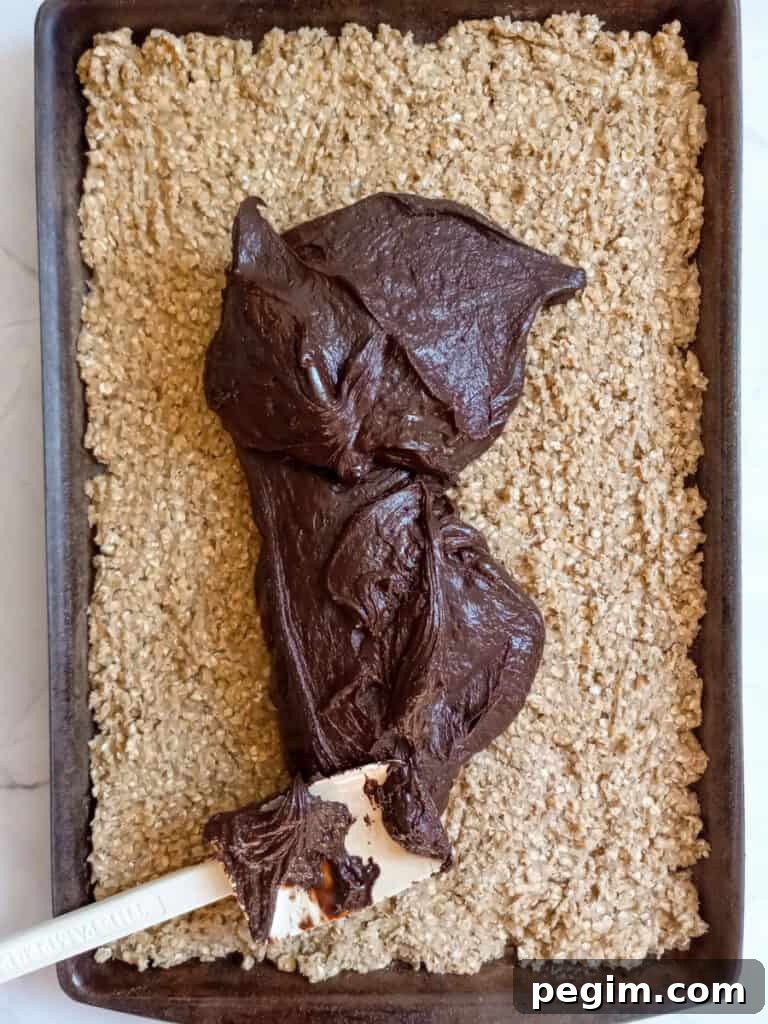 spreading the fudge over the oatmeal base.