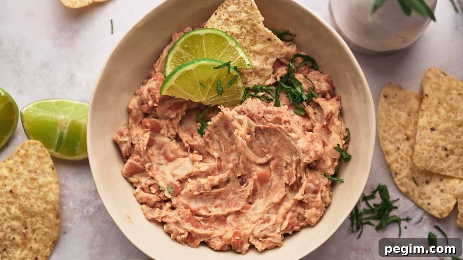 A bowl of homemade refried beans and lime wedges.