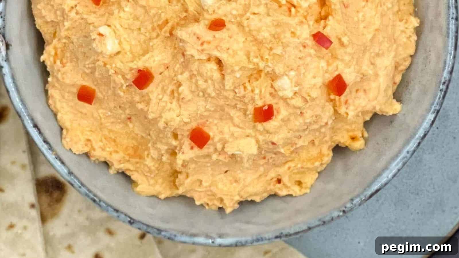 Spicy Greek feta dip in a bowl with pita bread by the side.