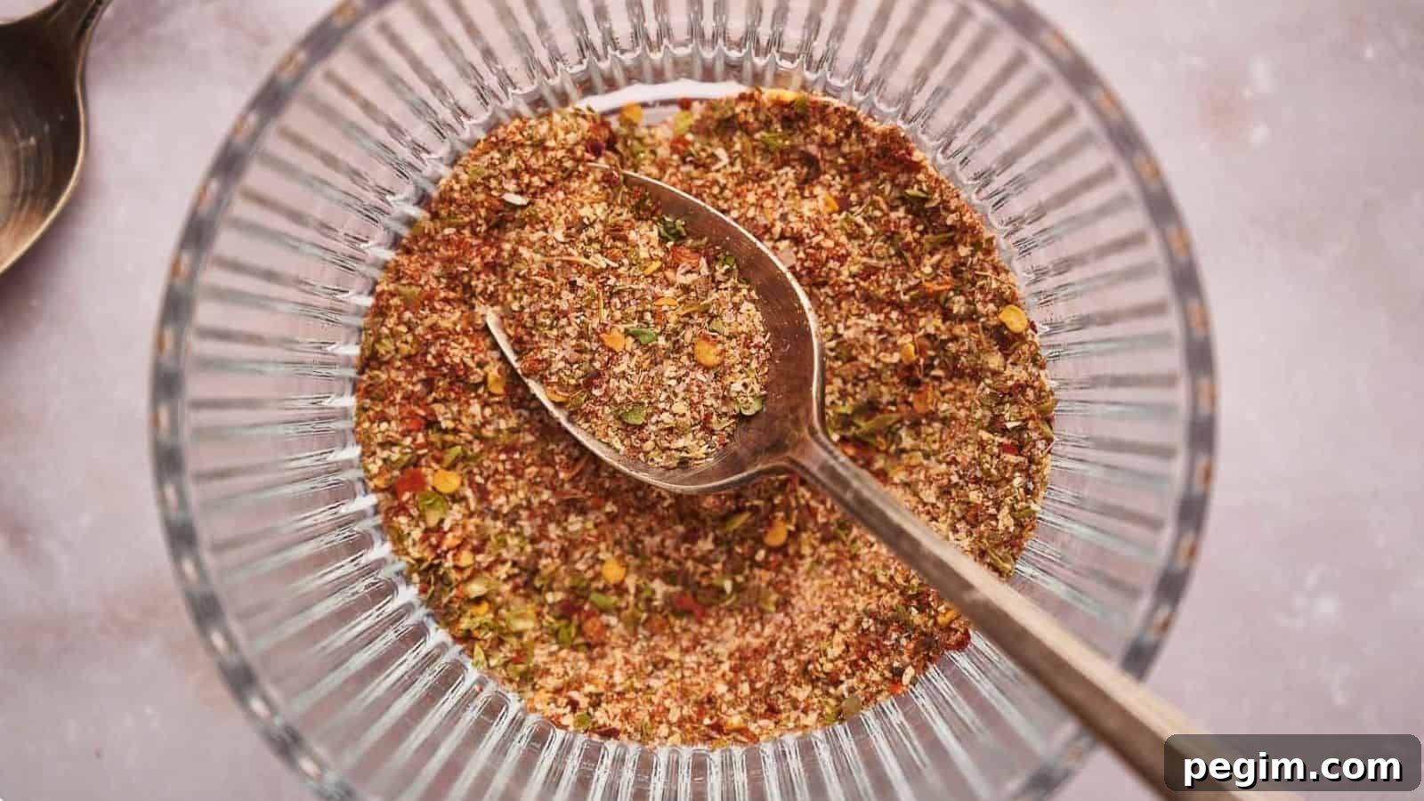 Taco seasoning in a glass bowl with a teaspoon in it.