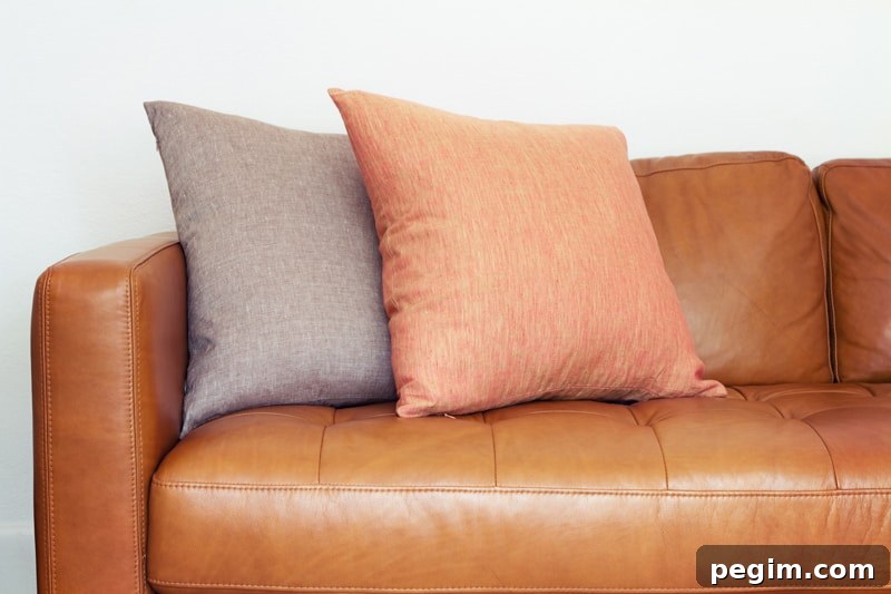 Leather couch with two throw pillows sitting on it.