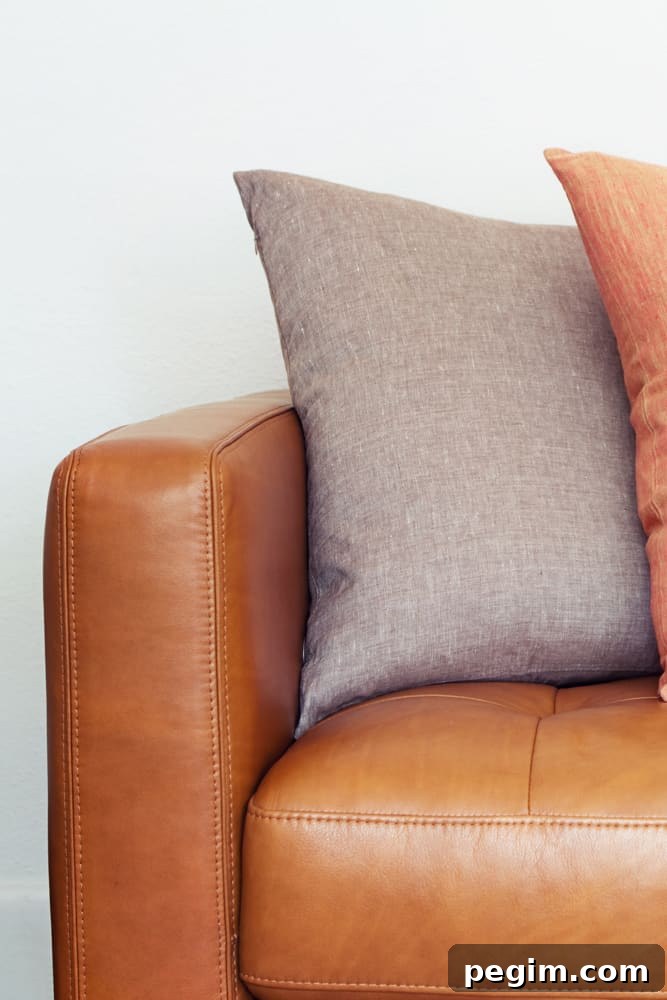Up close picture of leather couch with throw pillows on it.