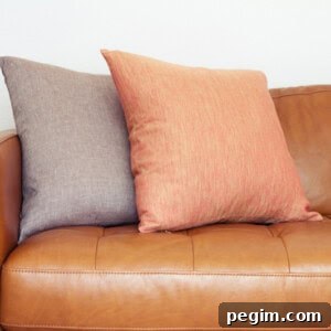 A leather sofa with throw pillows on it.