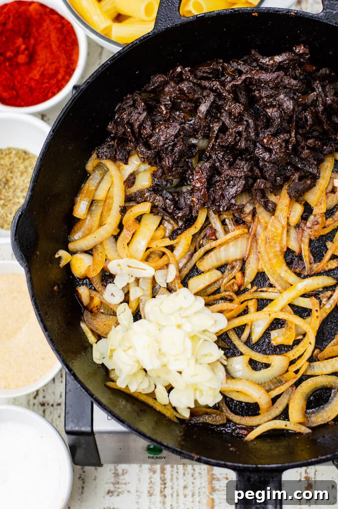 A cast iron skillet with sauteed onions, sun-dried tomatoes and sliced garlic.