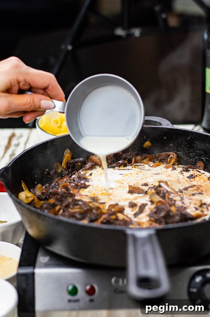 Cream is being poured into a skillet of sauteed onions and sun-dried tomatoes.