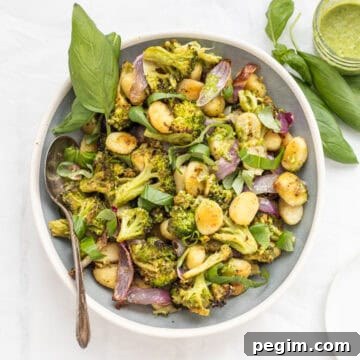 Sheet pan pesto gnocchi in a serving dish with a basil garnish.