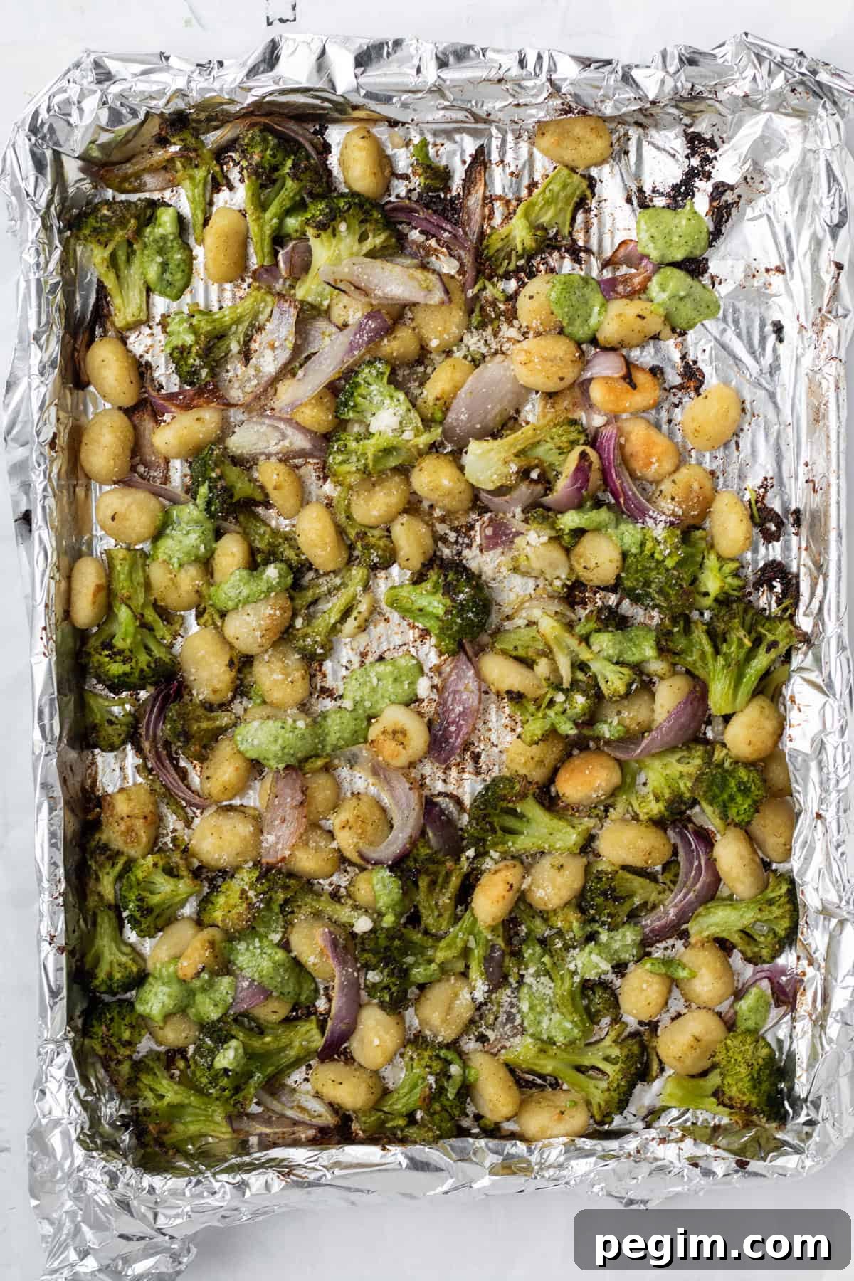 cooked sheet pan gnocchi with pesto on a foil lined sheet pan.