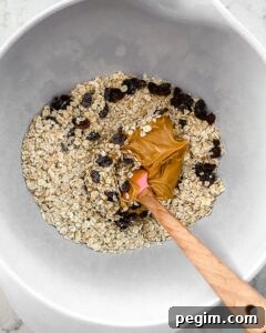 process of mixing ingredients of Oatmeal Raisin Protein Balls in a white bowl