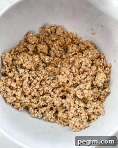 process of mixing ingredients of Oatmeal Raisin Protein Balls in a white bowl