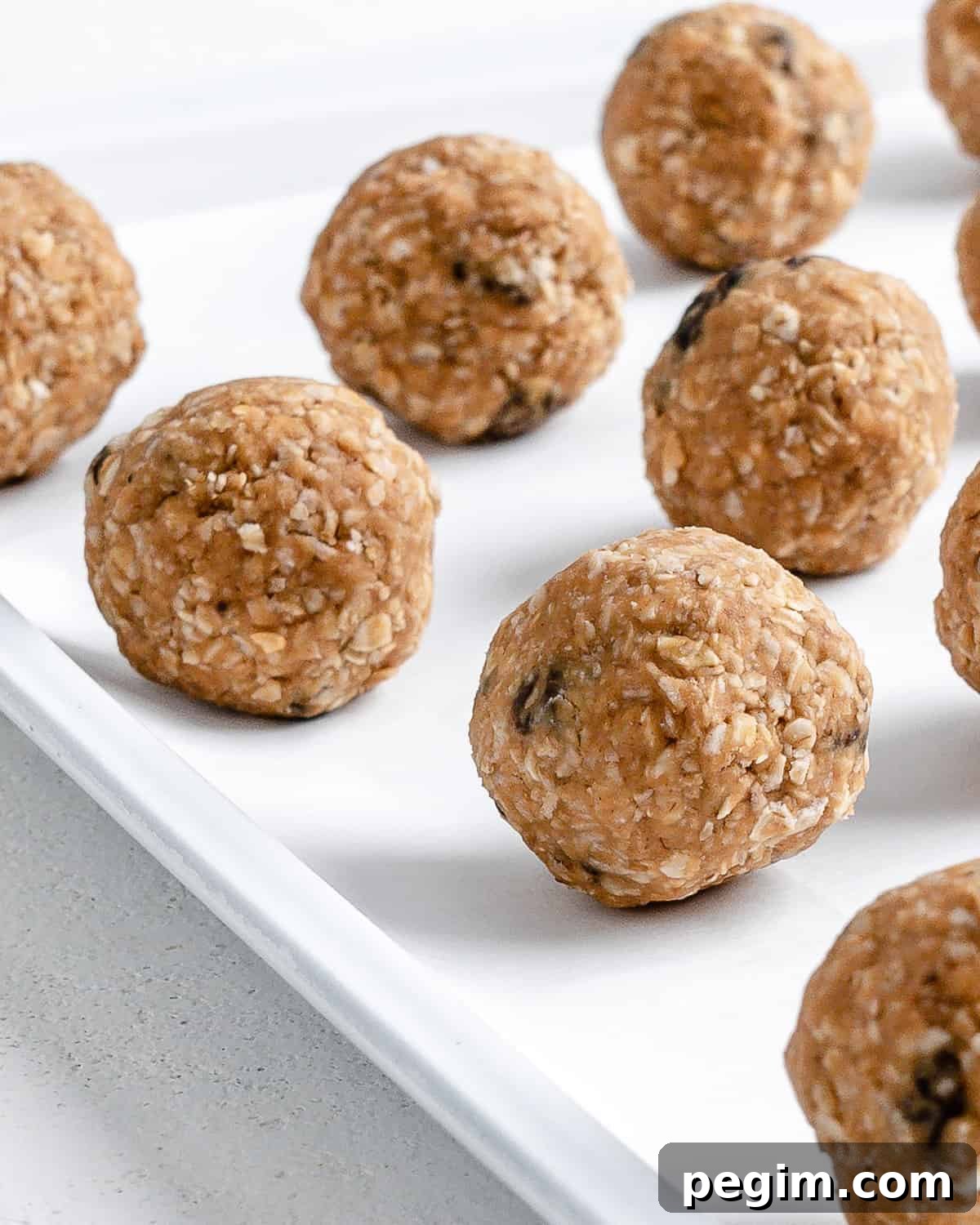 Oatmeal Raisin Protein Balls into balls on a white tray surface