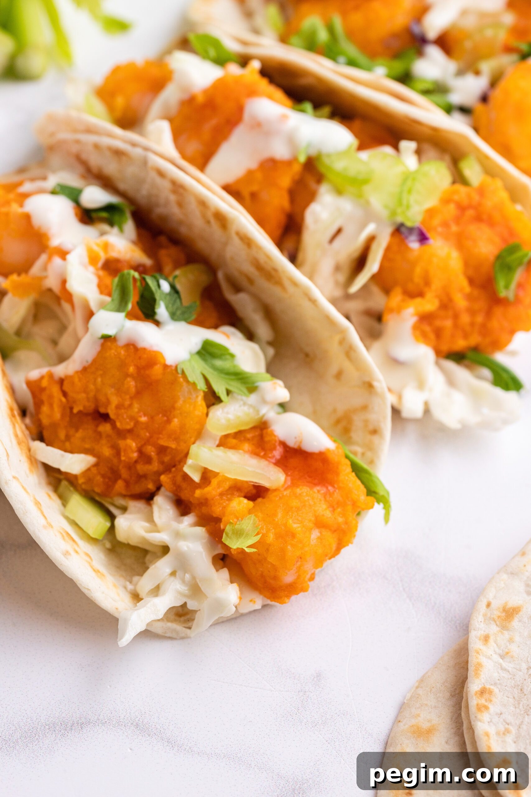 Buffalo shrimp tacos with cabbage slaw and a cream drizzle.