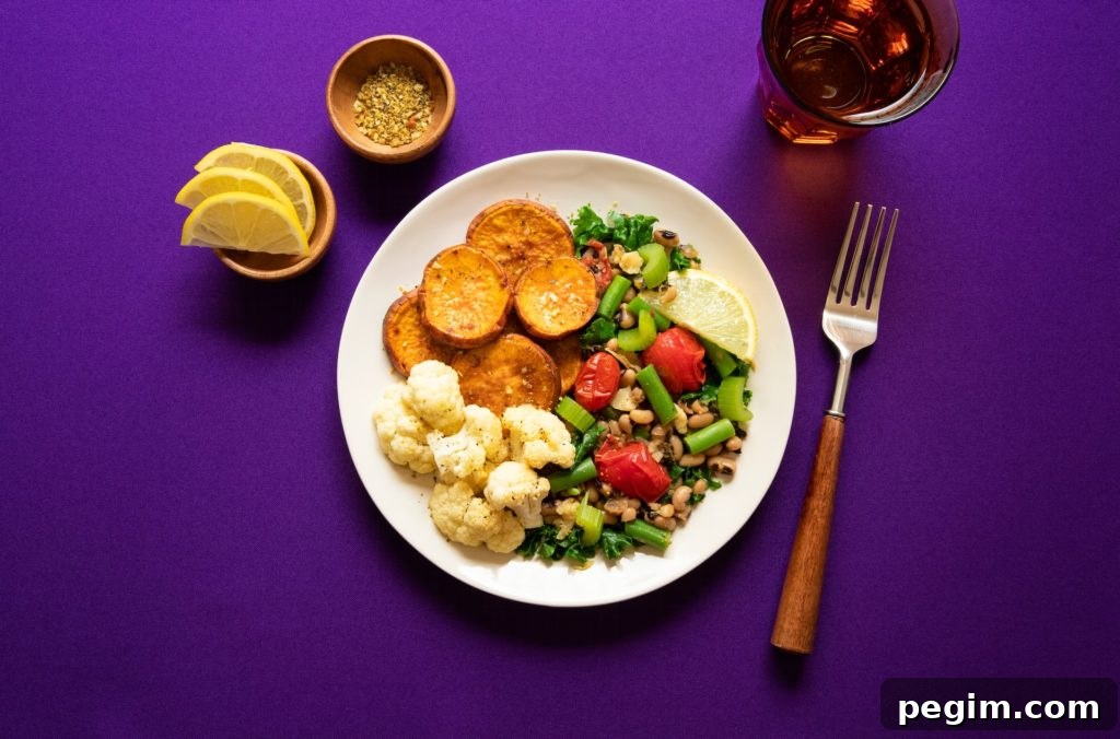 a balanced plate with sweet potatoes, cauliflower and black eyed peas on a purple countertop. 