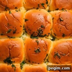 Golden brown dinner rolls topped with fresh herbs.