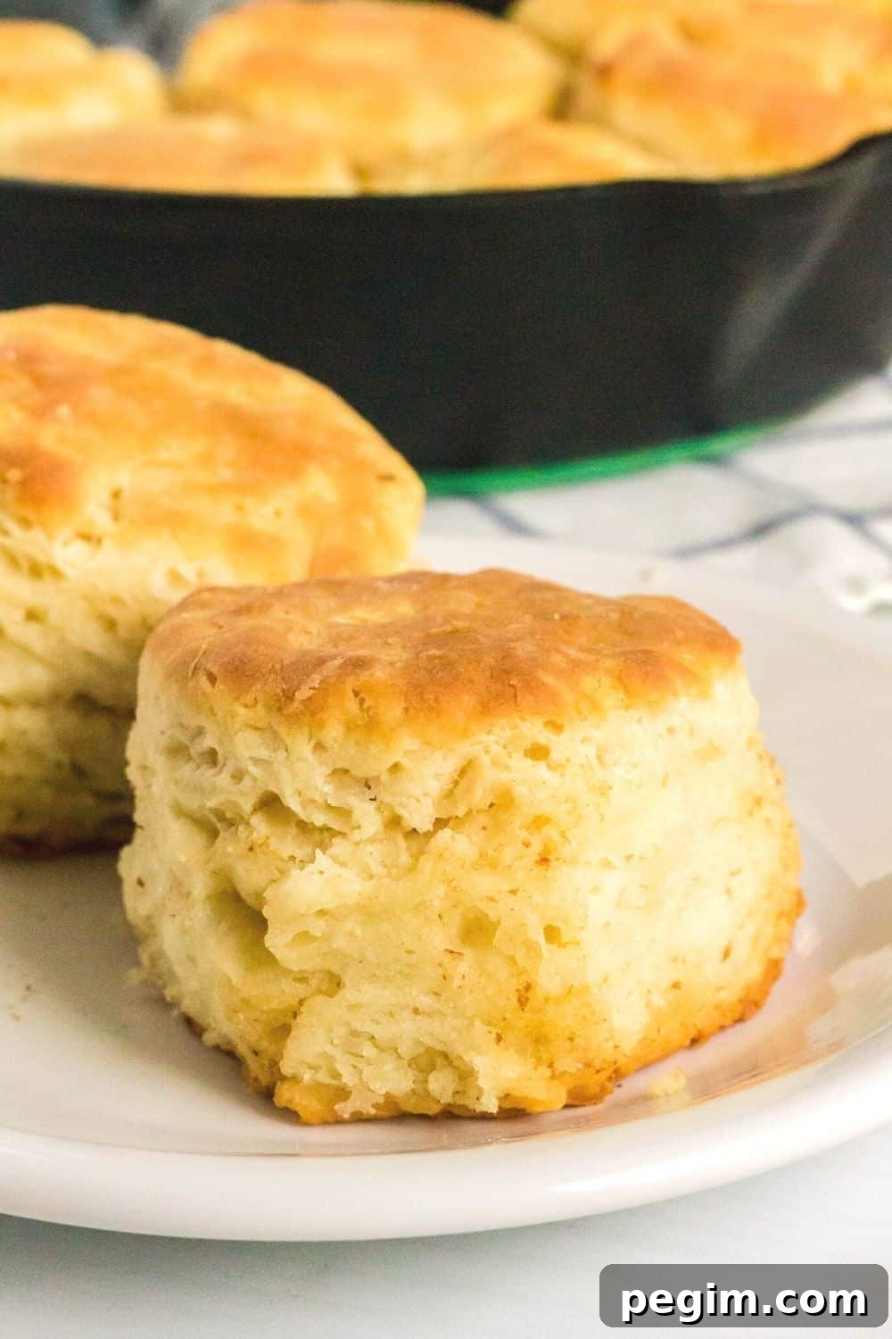 close-up side view of a homemade sour cream biscuit on a white plate