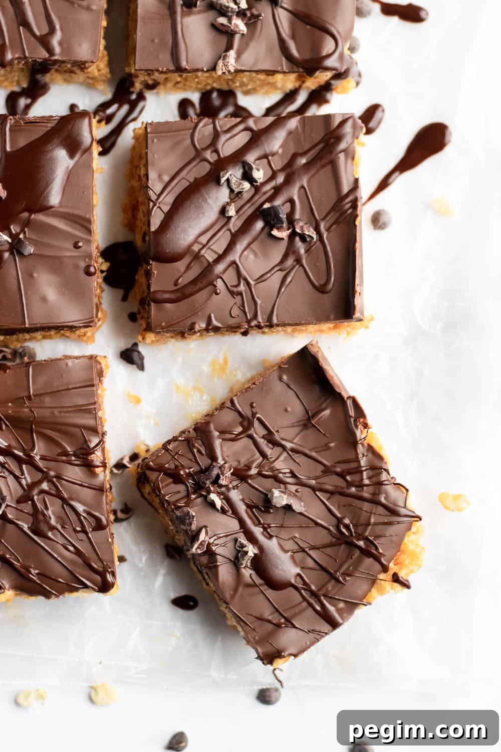 Chocolate Peanut Butter Rice Krispie Bars for Dessert 2 Chocolate peanut butter rice krispie treats with chocolate drizzle and chocolate chips on parchment.