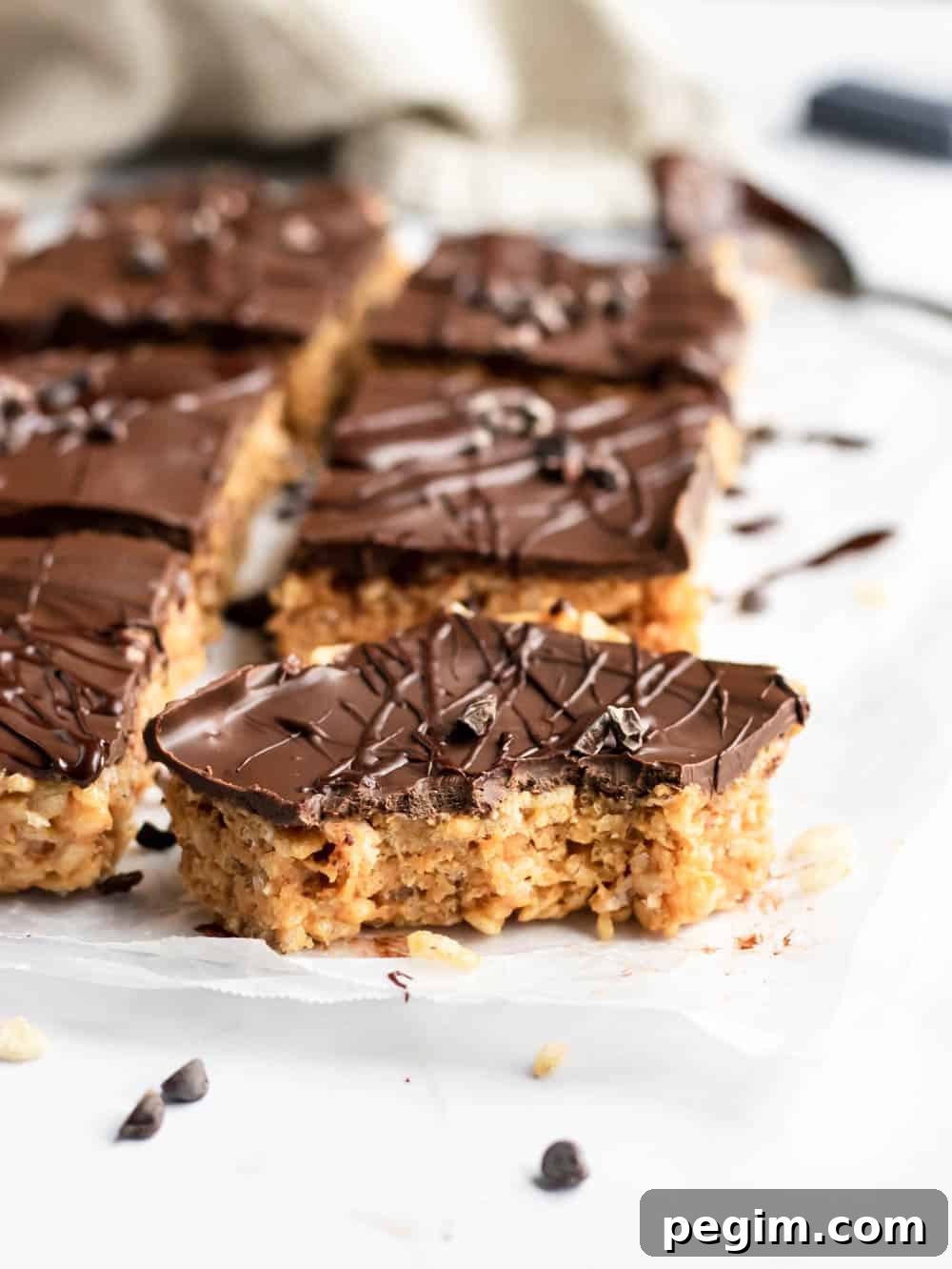 Chocolate Peanut Butter Rice Krispie Bars for Dessert 3 Sliced rice crispy treats with peanut butter and chocolate layer with bite taken out of front piece.