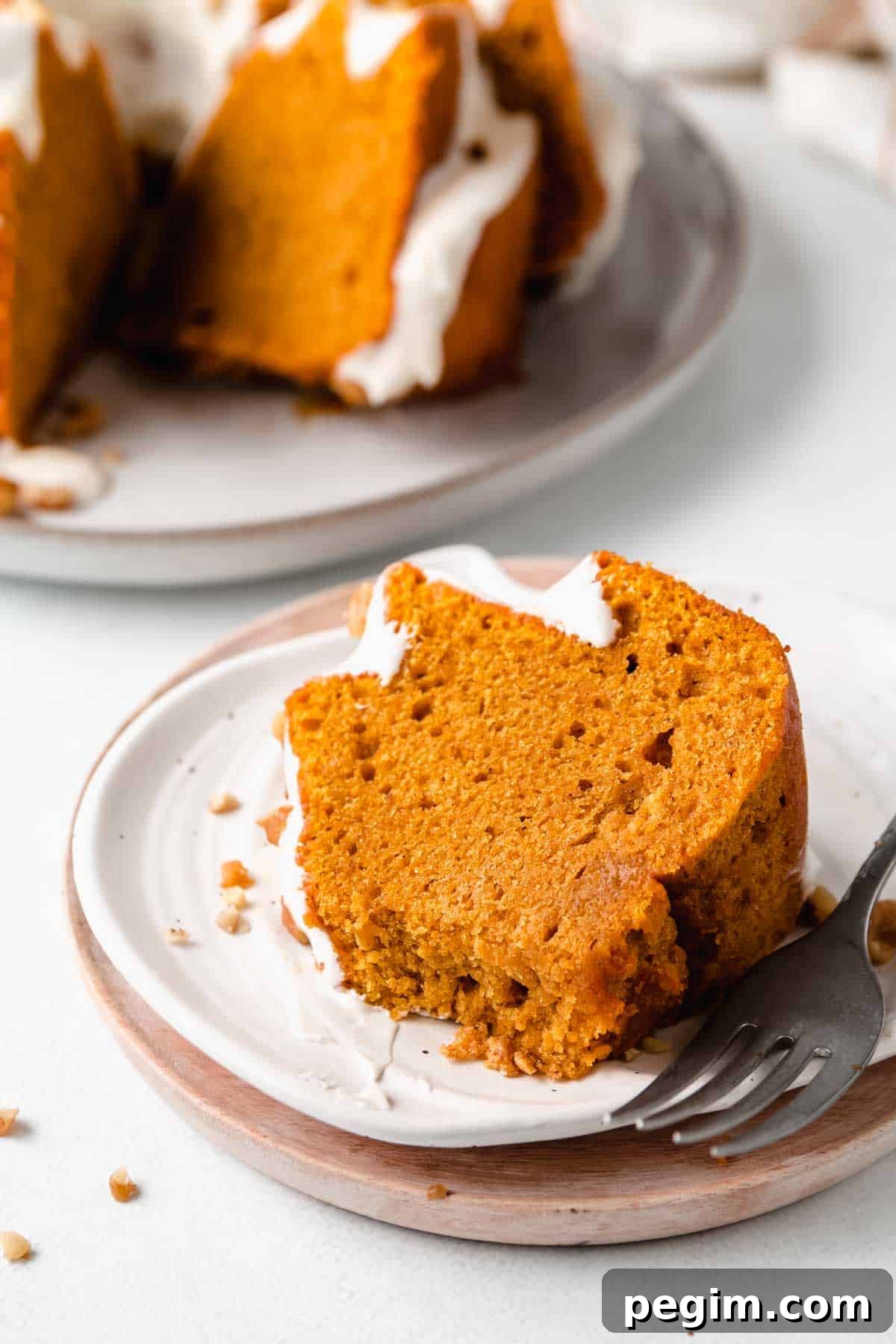 A slice of gluten-free pumpkin cake on a pumpkin shaped plate, with bite removed, next to a fork. 