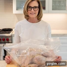 A whole fresh turkey in a brining bag on a cutting board.